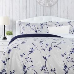 a bed with blue and white floral comforter set on it's headboard