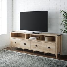 a flat screen tv sitting on top of a wooden entertainment center next to a window