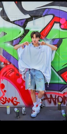 a man standing in front of a wall covered in graffiti