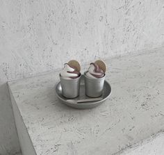 two pairs of shoes sitting on top of a metal tray next to a white wall