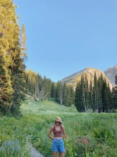 a woman standing on a trail in the mountains