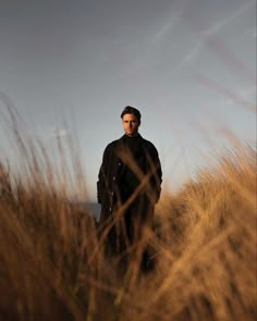 a man standing in tall grass on top of a hill