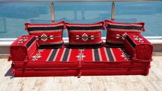 a red couch sitting on top of a wooden floor next to a large glass window