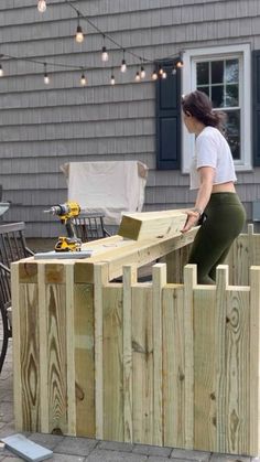 a woman is working on a wooden fence