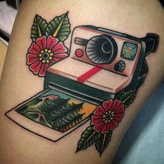 a tattoo with a camera and flowers on it