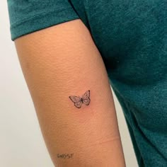 a woman's arm with a small butterfly tattoo on the back of her left arm