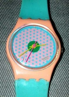 a pink and blue watch with polka dots on it's face sitting on a gray surface