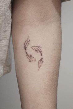 a man's arm with a small black fish tattoo on the left side of his leg