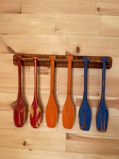 five wooden spoons are hanging on a wood rack in the shape of paddles