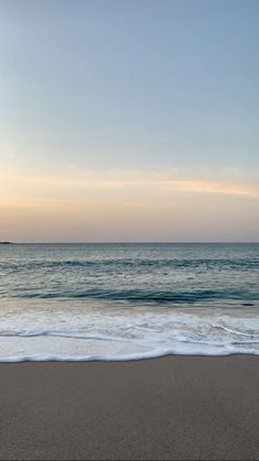 an empty beach with waves coming in to shore