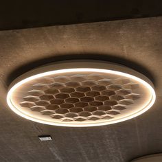 a circular light fixture in the middle of a concrete ceiling with hexagonal tiles on it