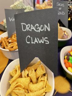 a table topped with bowls filled with different types of candy candies and dragon claws