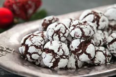 chocolate crinkle cookies with powdered sugar are on a silver platter next to red roses