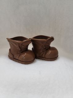 a pair of brown baby boots sitting on top of a white surface