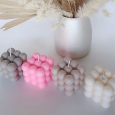 three candles sitting next to each other in front of a vase with feathers on it