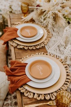 the table is set with plates and napkins on it, along with other place settings