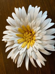 a white and yellow flower sitting on top of a wooden table