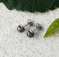 These small glass studs are mainly grey with flecks of black - a great neutral colour for everyday wear. Made from grey, black and clear crushed glass (frit) they have been fired in my kiln to 720oC, recut and fired again to 804oC. Produced in small batches, each stud is unique due to the random nature of the glass frit. Set in a stainless steel mounts, these earrings should be suitable for most earlobes, and will need minimal maintenance - wipe clean with a cloth and warm soapy water. Each earring measures approx. 7x15mm and the glass is handmade.  Free 2nd class postage for UK orders. Will combine postage for multiple orders. Grey Earrings, Glass Frit, Gray Earrings, Crushed Glass, Steel Grey, Hypoallergenic Earrings, Soapy Water, Ear Studs, Small Batches