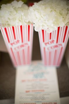 two red and white striped paper vases with flowers in them sitting on a table