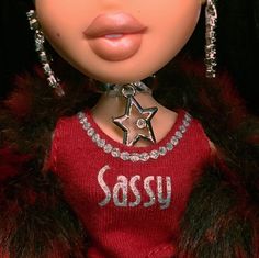 a close up of a doll wearing a red sweater and silver necklace with a star on it