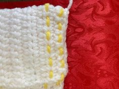 there is a crocheted piece of cloth with yellow buttons on it and a red background