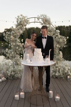 a newly married couple cutting their wedding cake at the end of an outdoor ceremony with candles