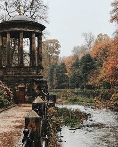 a gazebo sitting on the side of a river next to a forest filled with trees