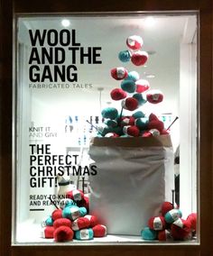 an advertisement for wool and the gang is displayed in a store window with red, white and blue pom - poms