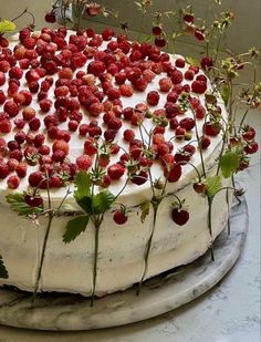 a cake with white frosting and fresh strawberries on top is sitting on a platter