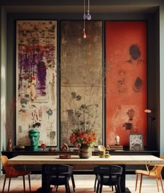 a dining room table with chairs and paintings on the wall in the backround