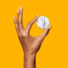 a person's hand holding a coin in front of an orange background