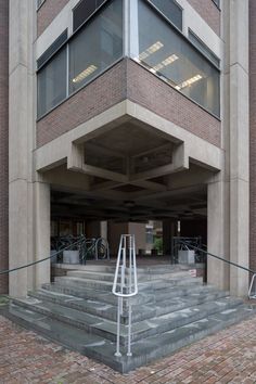 an entrance to a building with stairs leading up to the second floor and bicycles parked on the other side