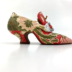 a pair of red and green shoes with floral designs on the heel, sitting against a white background