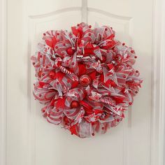 a red and white christmas wreath hanging on a door with candy canes attached to it