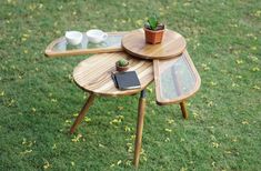 a wooden table with two trays on top of it and a potted plant next to it