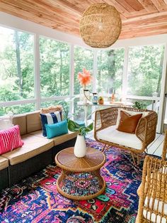 a living room with wicker furniture and colorful rugs on the floor in front of large windows