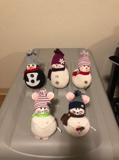 several stuffed animals sitting on top of a plastic container next to each other in hats