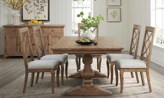 a dining room table with four chairs and a bowl of fruit on top of it