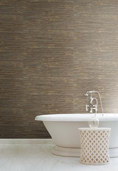 a white bath tub sitting next to a wall with a brown pattern on the walls