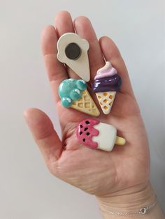 a hand holding several miniature ice creams and donuts