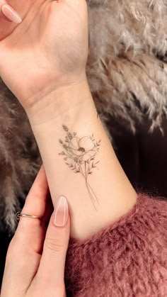 a woman's wrist with a flower tattoo on the left side of her arm