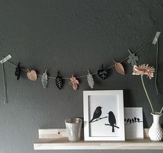 a bird is sitting on a branch with leaves hanging from it's sides, next to a framed photograph