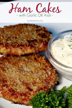 two crab cakes on a white plate with sour cream and parsley garnish