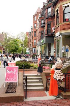 people are walking down the sidewalk in front of shops