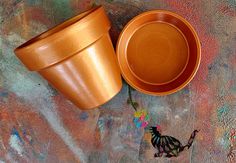 an orange pot sitting on top of a table next to a small bird figurine