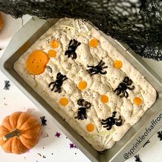 a halloween cake with white frosting and black spider decorations on it, surrounded by spooky pumpkins