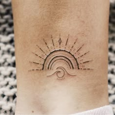 a woman's foot with a sun and wave tattoo on the side of her leg