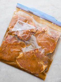 a bag filled with meat sitting on top of a white counter next to a knife