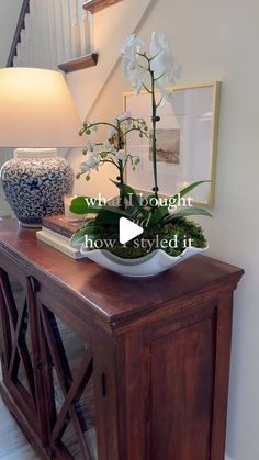 a vase with flowers sitting on top of a wooden table next to a stair case