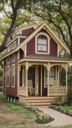 a small red and yellow house sitting on top of a lush green field next to trees